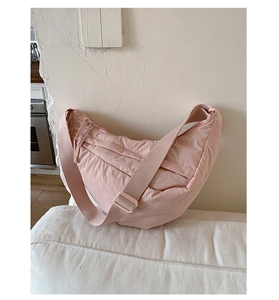 Detail of light pink crescent nylon crossbody bag with adjustable strap and zip closure