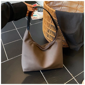 Détail d'un sac hobo en toile marron avec poignée en cuir noir et fermeture éclair