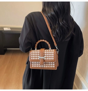 Detail of woven square handbag featuring twisted handle and silver buckle closure