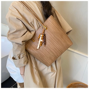 Dettaglio macro di una borsa tote intrecciata con nappa in legno e cinturino in pelle