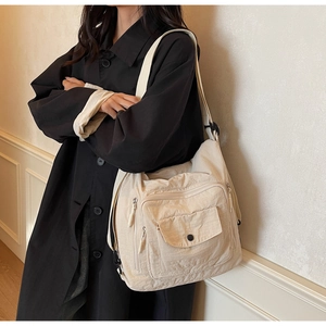 Detail of off-white multi-pocket tote bag with functional zippers and adjustable strap