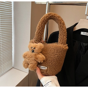 Détail du sac seau marron en polaire pelucheuse avec breloque ours et broderie élégante