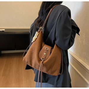 Detail of vintage brown suede tote bag with leather buckle and floral metal hardware