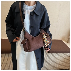Detail of a dark brown suede crescent bag with bohemian beaded tassel on shoulder strap
