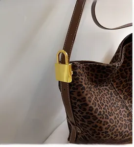 Close-up of leopard print tote with brown leather strap and gold padlock detail
