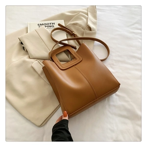 Close-up of caramel leather tote bag with unique square handle and stitch details
