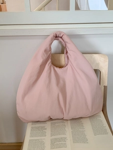 Pink puffy tote bag in minimalist dumpling style on a wooden chair with magazine