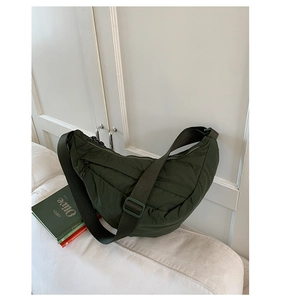 Close-up of olive green quilted dumpling bag on a soft white sofa in a minimalist room