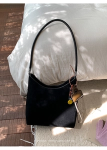 Detail of black suede tote bag with decorative charms and minimalist retro vibe texture
