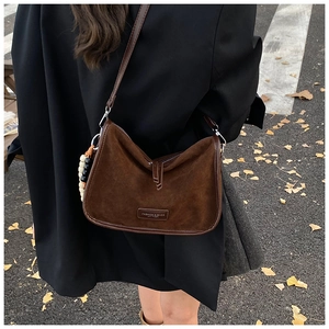 Braune Wildleder-Schultertasche im herbstlichen Streetstyle mit trockenem Laub