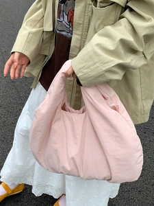 Pink puffy dumpling tote bag held by a model in a stylish outdoor street fashion look