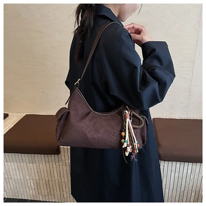 Detail of dark brown suede shoulder bag with tassel, beads and adjustable strap