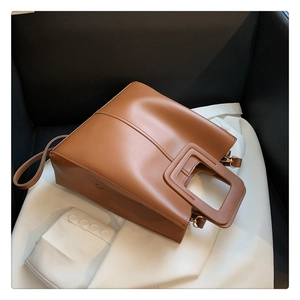Detailed close-up of brown leather tote bag featuring unique square cutout handles
