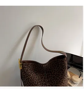 Detail of leopard print tote bag with brown leather straps and gold metal twist lock