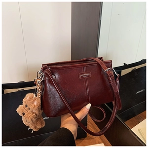 Vue détaillée d'un sac à main en cuir bordeaux avec un charmant pendentif d'ours