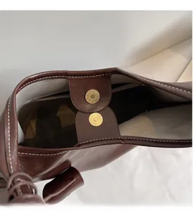 Detail of magnetic snap closure on brown leather tote with herringbone fabric lining