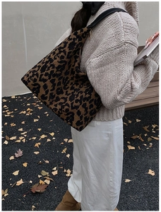 Detail der hobo-tasche mit leopardenmuster und schwarzen lederriemen am modell