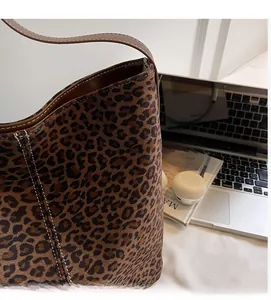 Detail of leopard print tote bag featuring brown leather strap and contrast stitching