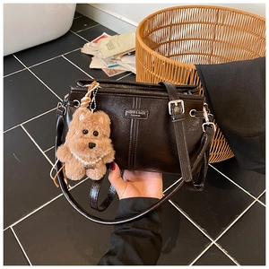 Détail d'un sac à main vintage en similicuir avec breloque ours et plaque logo métal