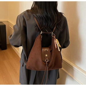 Détail du sac cabas vintage en daim avec boucle fleurie dorée et breloque en perles