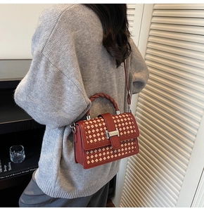 Detailed view of red-brown woven crossbody bag with silver metal H-shaped buckle clasp