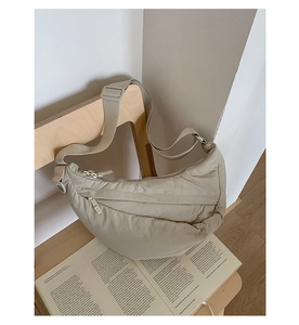 Detail of khaki nylon crescent bag featuring wide adjustable strap and zipper pockets