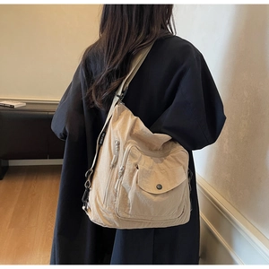 Detail of beige large capacity crossbody bag showing wide strap and brand label