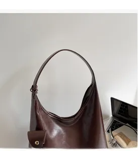 Detail of a dark brown glossy leather hobo bag with wide shoulder strap in a home office set
