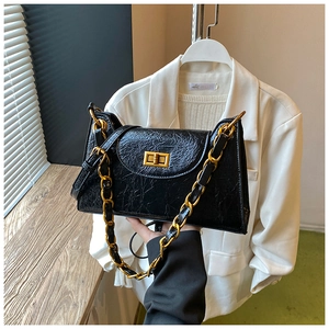 Detailed shot of black crinkled patent leather shoulder bag with gold chunky chain strap