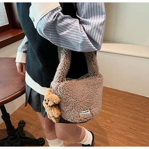 Detail of a brown plush bucket bag featuring a bear pendant and woven brand label