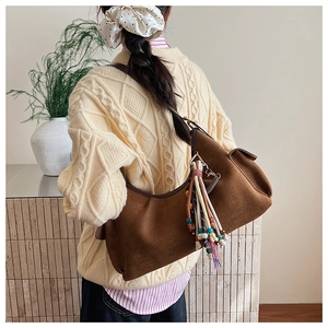 Detail of brown faux suede hobo bag with ethnic style beaded tassel charm on shoulder strap