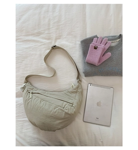 Detailed flat lay of a beige crescent crossbody bag with knit gloves on white fabric