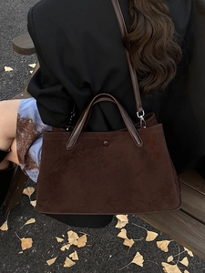 Deep brown matte suede tote bag with leather straps in an autumn outdoor setting