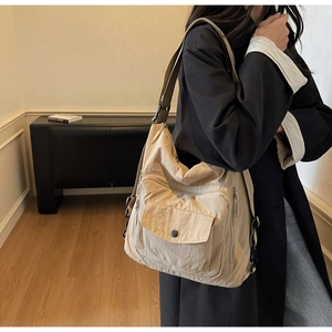 Detail of beige canvas crossbody bag featuring multi-pocket design and wide shoulder strap