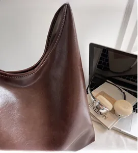 Detail of brown leather tote featuring white contrast stitching and herringbone lining