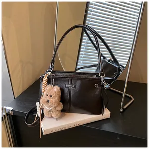 Détail du sac à main en cuir noir avec logo en métal et charmant chiot en peluche marron