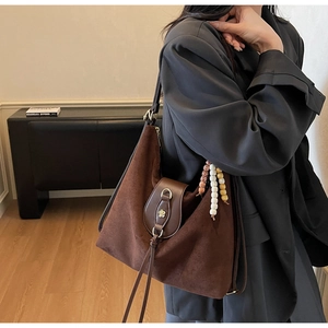 Detail of a dark coffee frosted suede tote with leather tassels and boho beaded charms