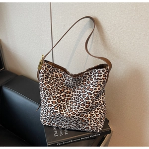 Close-up of leopard print canvas tote with brown leather strap and gold metal buckle
