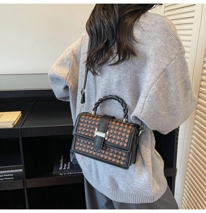 Close-up of woven checkered pattern handbag with twisted handle and silver metal clasp