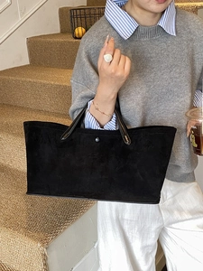 Minimalist black suede tote bag with leather handles and a large capacity for travel