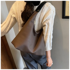 Détail d'un grand sac à bandoulière marron foncé avec large sangle noire sur mannequin