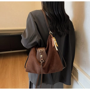 Detail of dark brown faux suede tote bag with floral metal snaps and beaded tassel charm