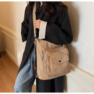 Close-up of khaki nylon tote bag with multiple pockets and wide beige shoulder strap