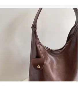 Detail of dark brown tote bag featuring handcrafted knot strap and a mini pouch charm