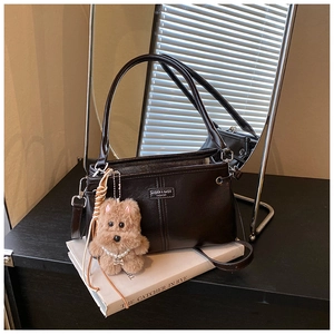 Détail d'un sac à main vintage en cuir avec un charme de chiot et collier de perles