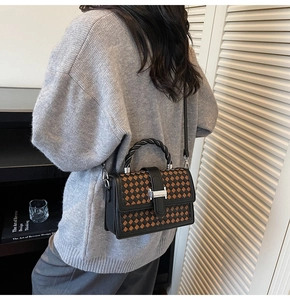 Close-up of dual-tone woven texture and H-shaped metal buckle on women's handbag