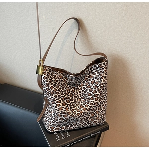 Detail view of the brown leather shoulder strap and golden metal lock on the leopard tote