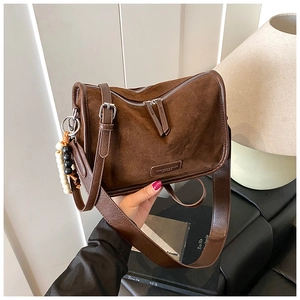 Detail der braunen Vintage-Tasche mit Doppel-Reißverschluss und dekorativem Perlenanhänger