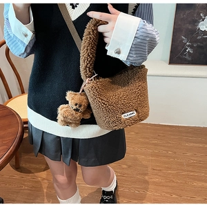 Detail of brown plush crossbody bag with teddy bear charm and soft fleece texture