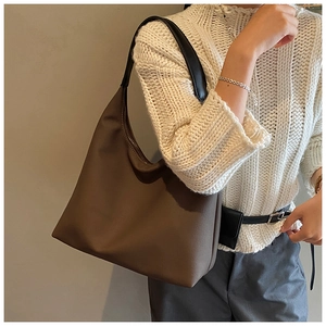 Détail d'un sac fourre-tout marron en forme de croissant avec texture mate et anse